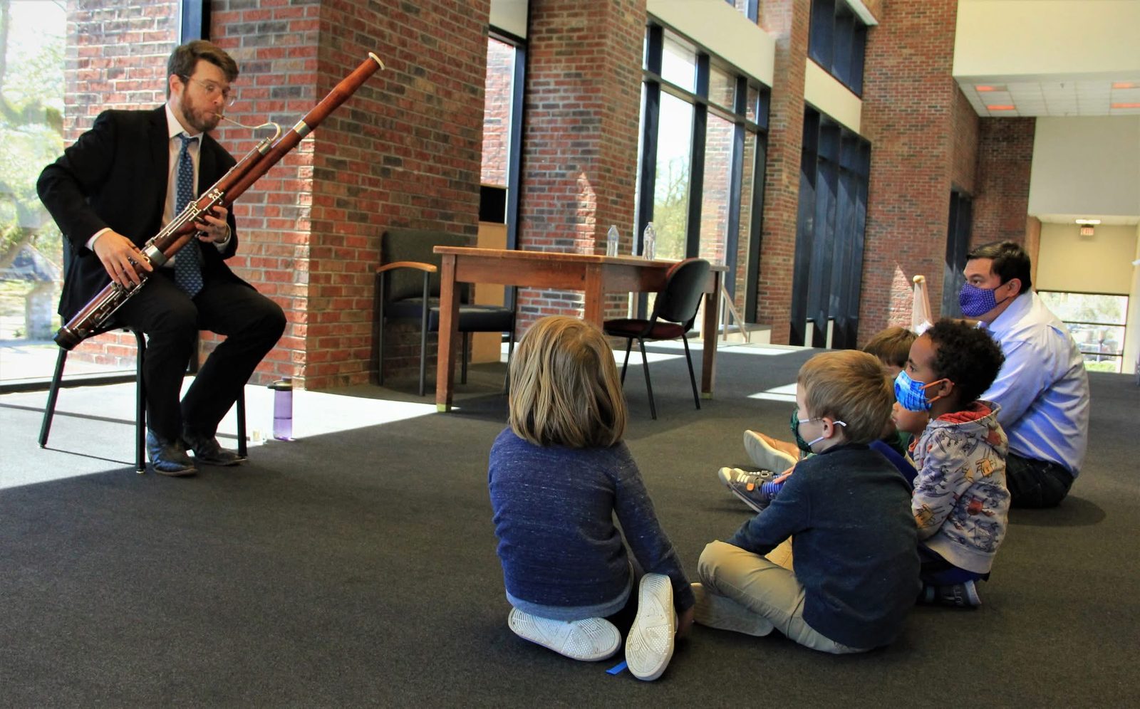 Michael Matushek playing bassoon for a group of young children seated on the floor